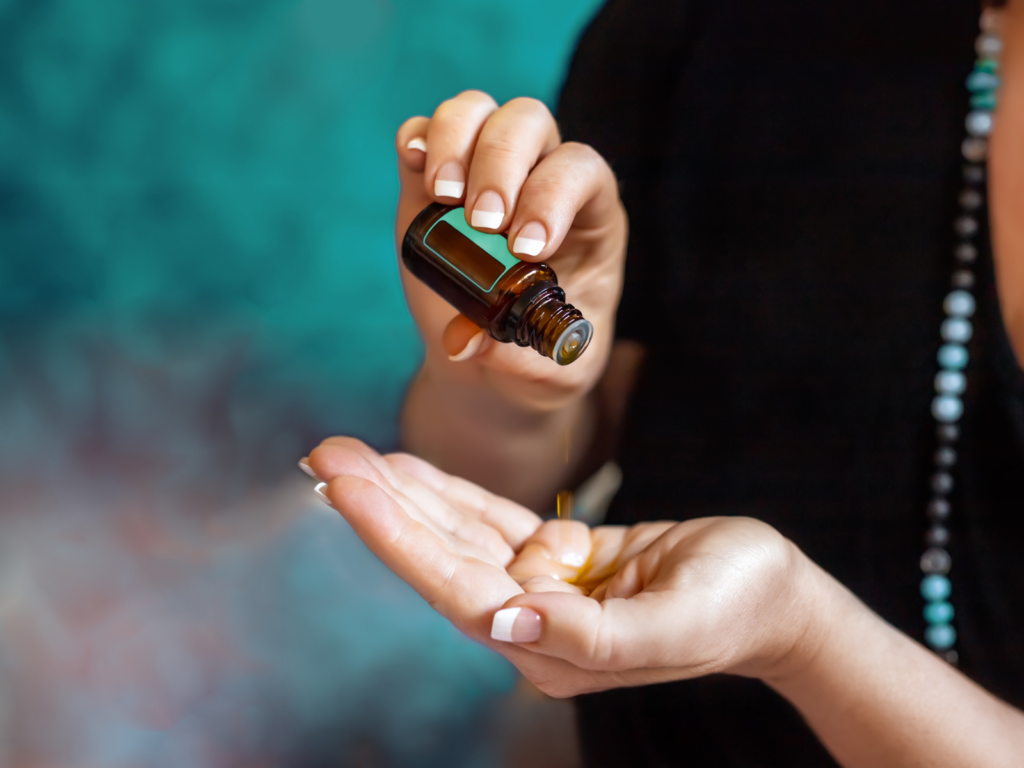 Foto ilustra mulher aplicando óleo essencial para aromaterapia na mão